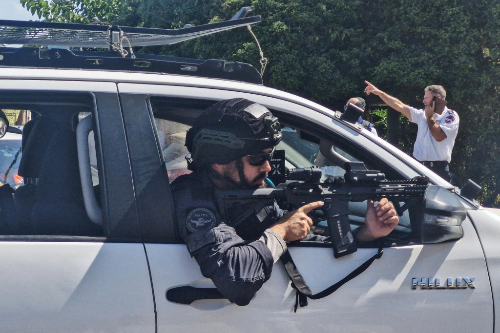 Izraelský policajt mieri zbraňou z vozidla po podozrení z útoku nožom v izraelskom meste Chadera. FOTO: Reuters