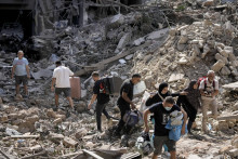 Obyvatelia kráčajú v troskách zničených obytných budov so svojimi vecami po štvrtkovom izraelskom leteckom útoku v Bejrúte. FOTO: TASR/AP