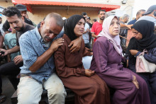 Smútiaci sedia pri telách Palestínčanov, ktorí boli zabití pri izraelskom údere uprostred konfliktu medzi Izraelom a Hamasom. FOTO: Reuters