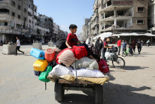 Vysídlený palestínsky chlapec sedí na vozíku, keď spolu s ďalšími odchádza na útek z oblastí v severnom pásme Gazy. FOTO: Reuters