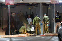 Izraelskí vojaci a ďalší ľudia po útoku bezpilotného lietadla z Libanonu zložili nosné vozíky. FOTO: Reuters