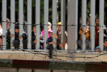 Migranti stoja pri múre na poľsko-bieloruskej hranici neďaleko poľského mesta Bialowieza. FOTO: REUTERS