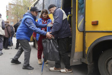 Dobrovoľník pomáha staršiemu mužovi evakuovanému z mesta Kupiansk v distribučnom centre pre vnútorne vysídlené osoby v Charkove na Ukrajine. FOTO: TASR/AP