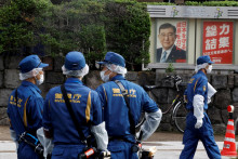 Plagát s japonským premiérom Šigeruom Išibom je za policajtmi vykonávajúcimi vyšetrovanie v sídle Liberálno-demokratickej strany v Tokiu. FOTO: Reuters