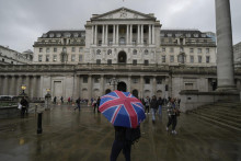 Na archívnej snímke žena s dáždnikom stojí pred centrálnou bankou Bank of England v Londýne. FOTO: TASR/AP