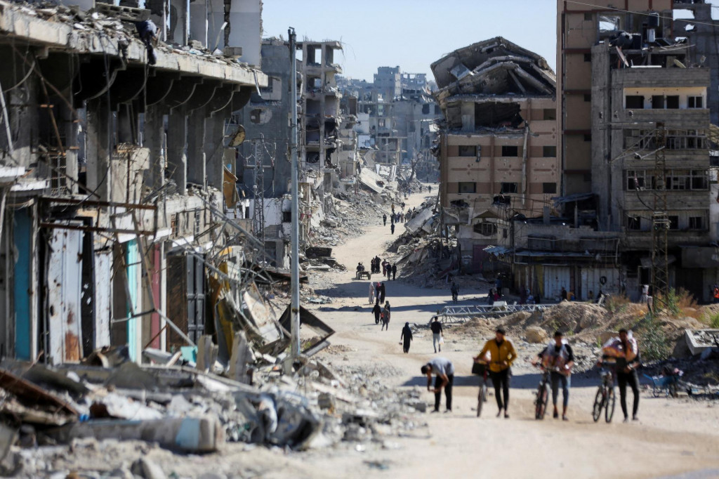 Palestínčania prechádzajú zničenou štvrťou v Gaze. FOTO: Reuters