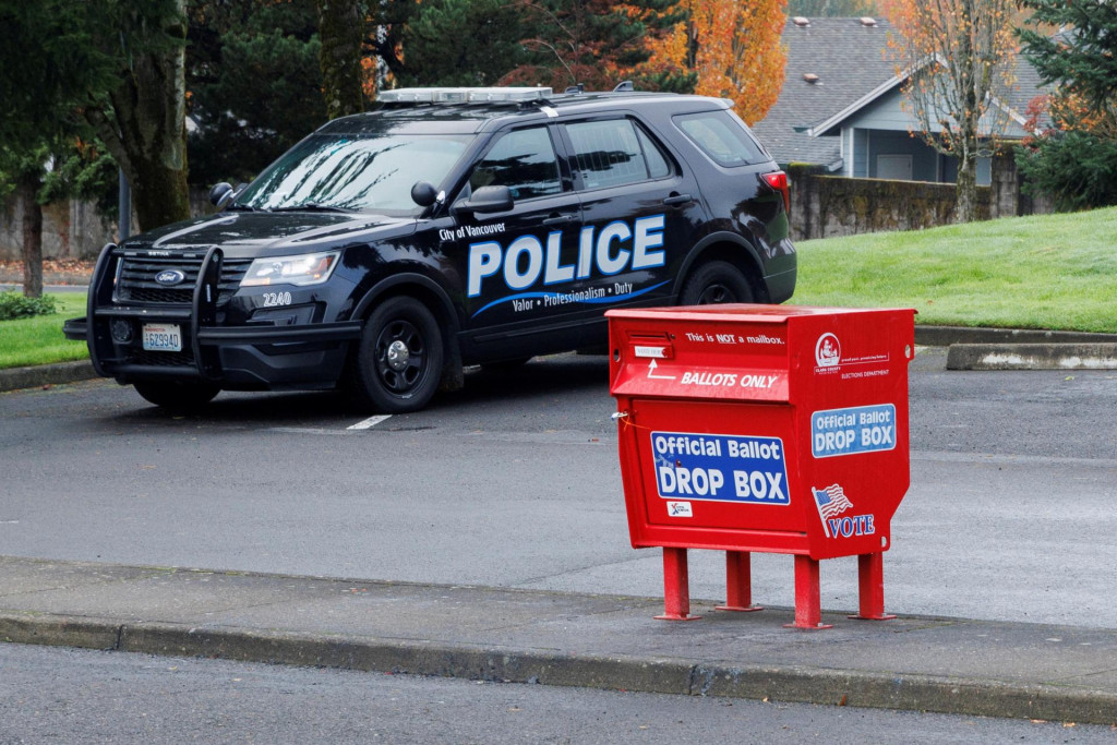 Policajt z vancouverského policajného oddelenia sleduje novú volebnú urnu, ktorú vymenili po tom, čo ju niekto podpálil. FOTO: Reuters