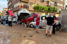 Ľudia stoja pri autách nahromadených na obytnej ulici v dôsledku prívalových dažďov, ktoré spôsobili záplavy v Alfafare vo Valencii. FOTO: Reuters