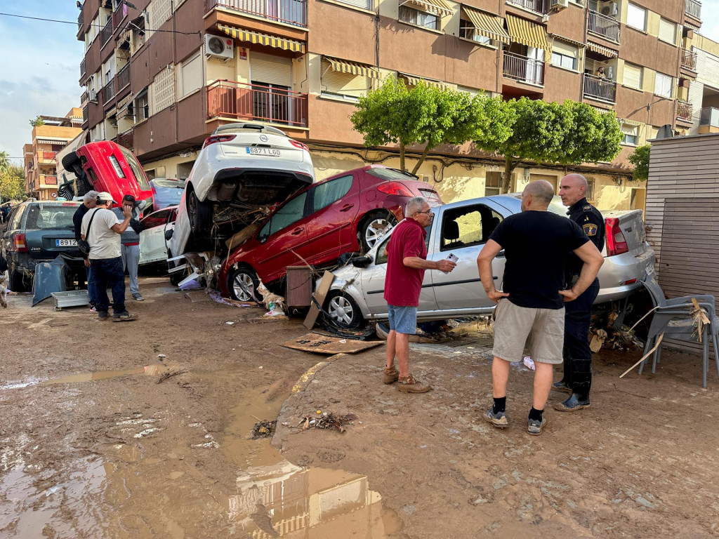 Ľudia stoja pri autách nahromadených na obytnej ulici v dôsledku prívalových dažďov, ktoré spôsobili záplavy v Alfafare vo Valencii. FOTO: Reuters