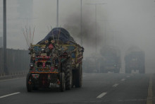 Traktor s vozíkom vypúšťa dym na ceste počas smogu v pakistanskom meste Láhaur. FOTO: TASR/AP