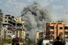 Palestínčania sledujú, ako stúpa dym po izraelských útokoch uprostred prebiehajúceho konfliktu medzi Izraelom a Hamasom v Nuseirate v centrálnom pásme Gazy.  FOTO: Reuters