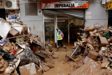 Ľudia kráčajú v blízkosti hromady trosiek po silných dažďoch, ktoré spôsobili záplavy, v Paiporta, neďaleko Valencie. FOTO: Reuters