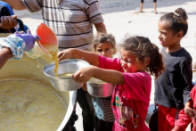 Palestínske deti sa zhromažďujú, aby dostali jedlo navarené v charitatívnej kuchyni uprostred konfliktu medzi Izraelom a Hamasom v Chán Júnise v južnom pásme Gazy. FOTO: Reuters