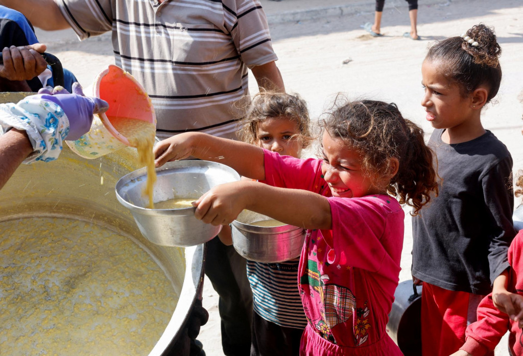 Palestínske deti sa zhromažďujú, aby dostali jedlo navarené v charitatívnej kuchyni uprostred konfliktu medzi Izraelom a Hamasom v Chán Júnise v južnom pásme Gazy. FOTO: Reuters