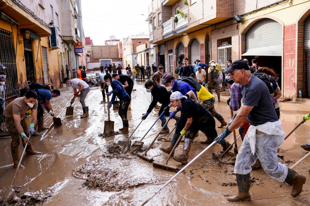 Ľudia čistia zablatenú ulicu po záplavách spôsobených silnými dažďami vo Valencii. FOTO: Reuters