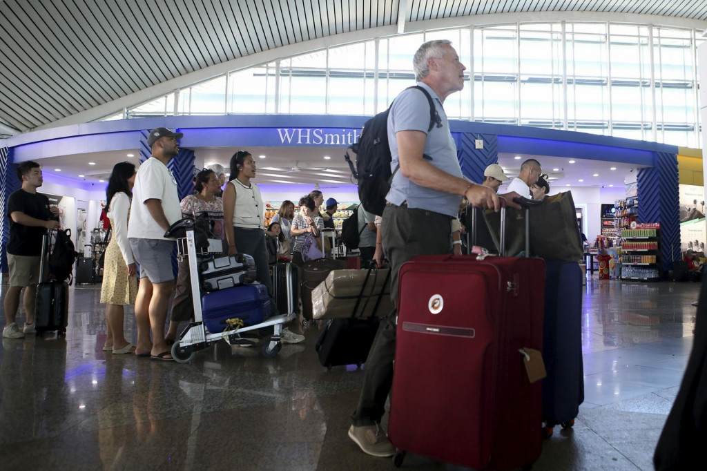 Cestujúci sa pozerajú na letovú informačnú tabuľu po tom, čo bolo niekoľko letov zrušených v dôsledku erupcie hory Lewotobi Laki-Laki na medzinárodnom letisku Ngurah Rai na Bali. FOTO: TASR/AP