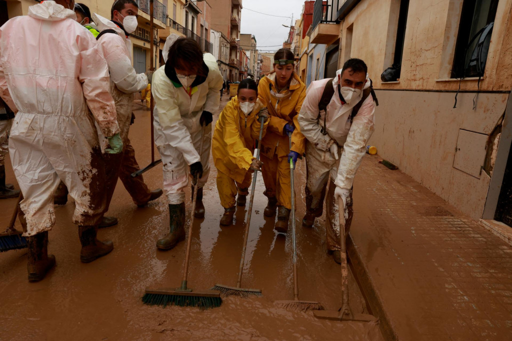 Dobrovoľníci čistia kalnú vodu po katastrofálnych záplavách vo Valencii. FOTO: Reuters