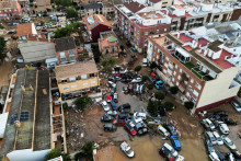 Letecký pohľad na autá a trosky nahromadené na ulici po povodniach vo Valencii.