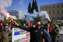 Protestujúci držia svetlice počas celonárodného generálneho štrajku organizovaného odbormi súkromného a verejného sektora, ktoré požadujú lepšie mzdy v Aténach. FOTO: TASR/AP