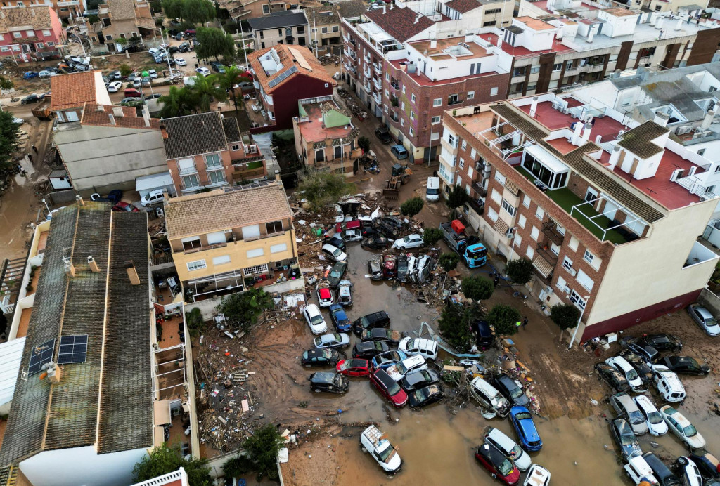 Letecký pohľad na autá a trosky nahromadené na ulici po povodniach vo Valencii.