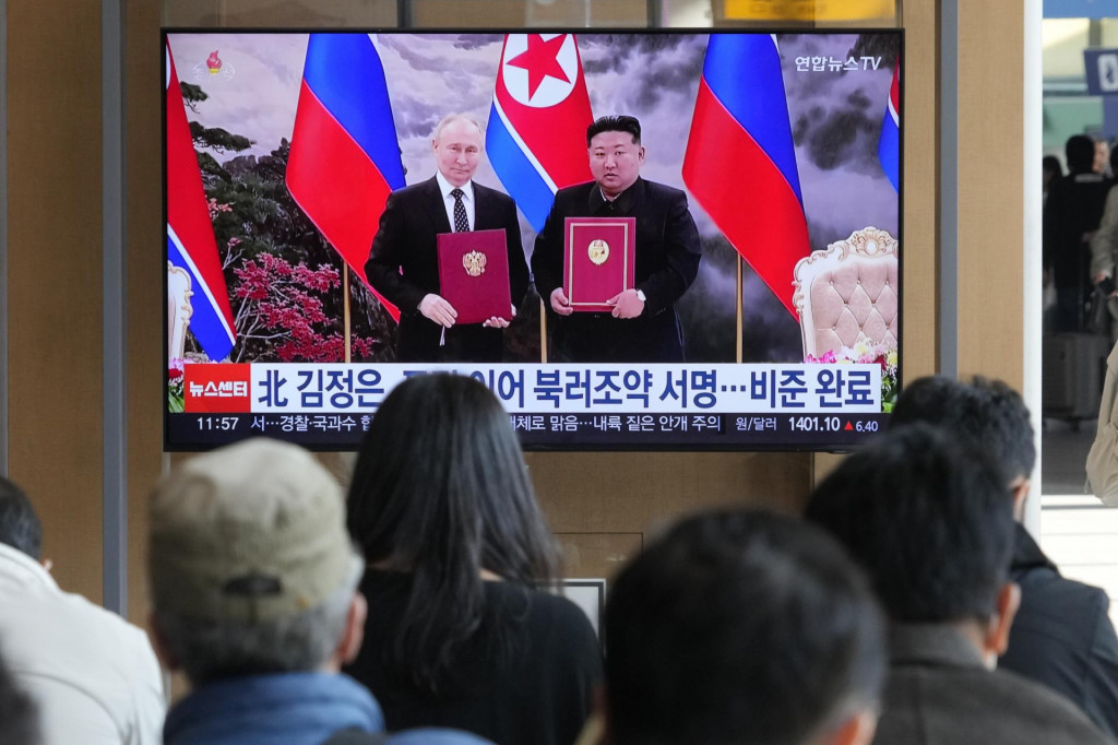 Ľudia sledujú na televíznej obrazovke archívne zábery ruského prezidenta Vladimira Putina a severokórejského lídra Kim Čong-una v Pchjongjangu. FOTO: TASR/AP