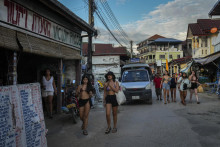 Zahraniční turisti kráčajú okolo barov na ulici v laoskom meste Vang Vieng. FOTO: TASR/AP