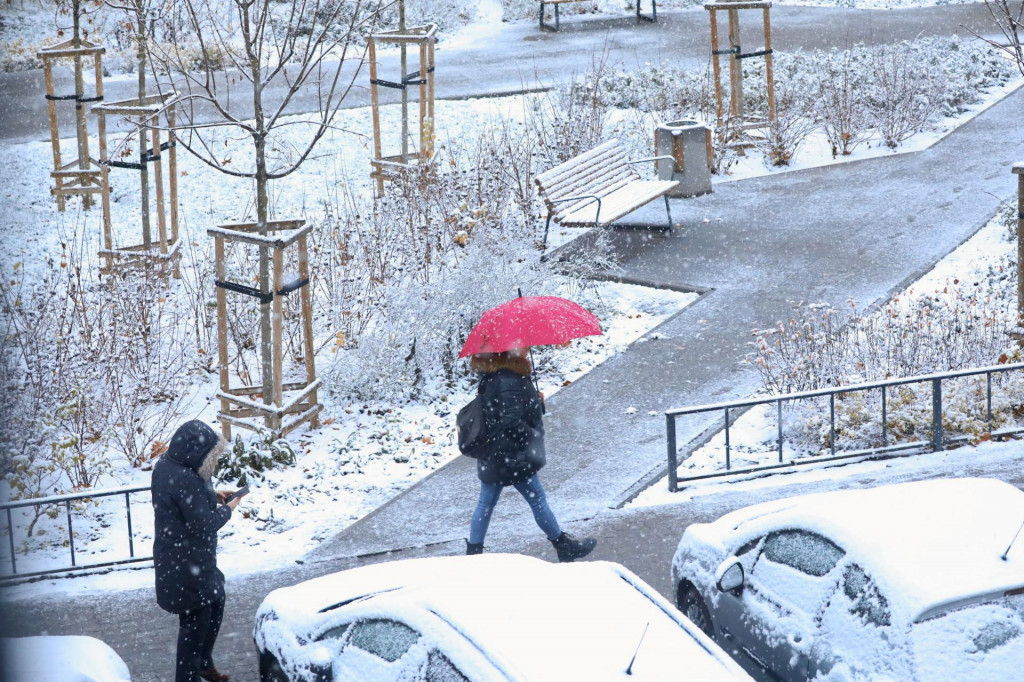 Žena používa dáždnik, aby sa zakryla pred snehom, keď sa prechádza vo Varšave v Poľsku. FOTO: Reuters