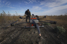 Dobrovoľníci sa pripravujú na spustenie dronu ukrajinskej výroby, ktorý hľadá míny na poli v blízkosti frontovej línie v Charkovskej oblasti na východe Ukrajiny. FOTO: TASR/AP