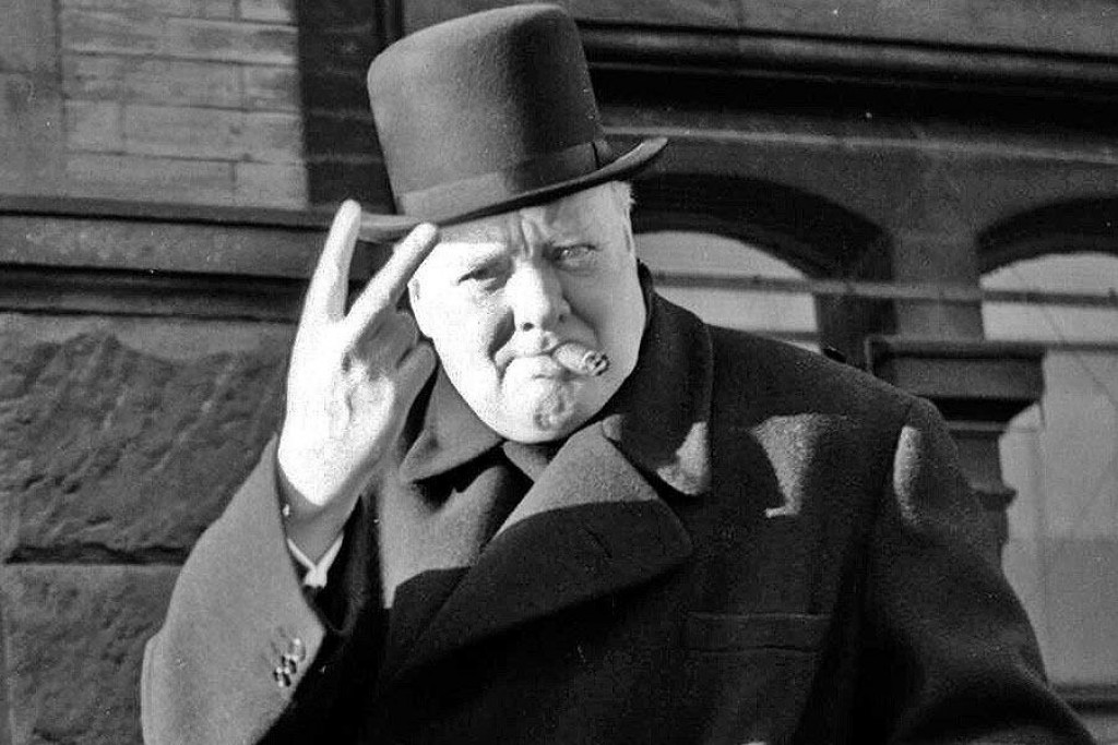 Bývalý britský premiér Winston Churchill (1874 – 1965) ukazuje svoje typické víťazné gesto.