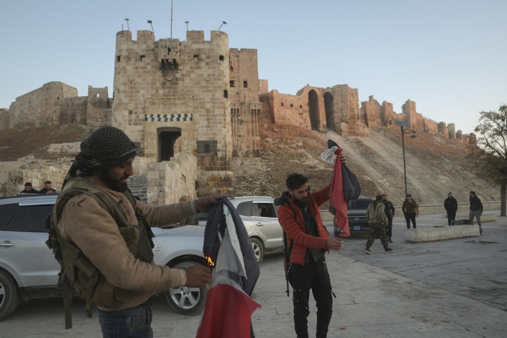 Sýrski opoziční bojovníci pália vládne sýrske vlajky pred kamerami v sýrskom meste Aleppo v sobotu 30. novembra 2024. FOTO: TASR/AP