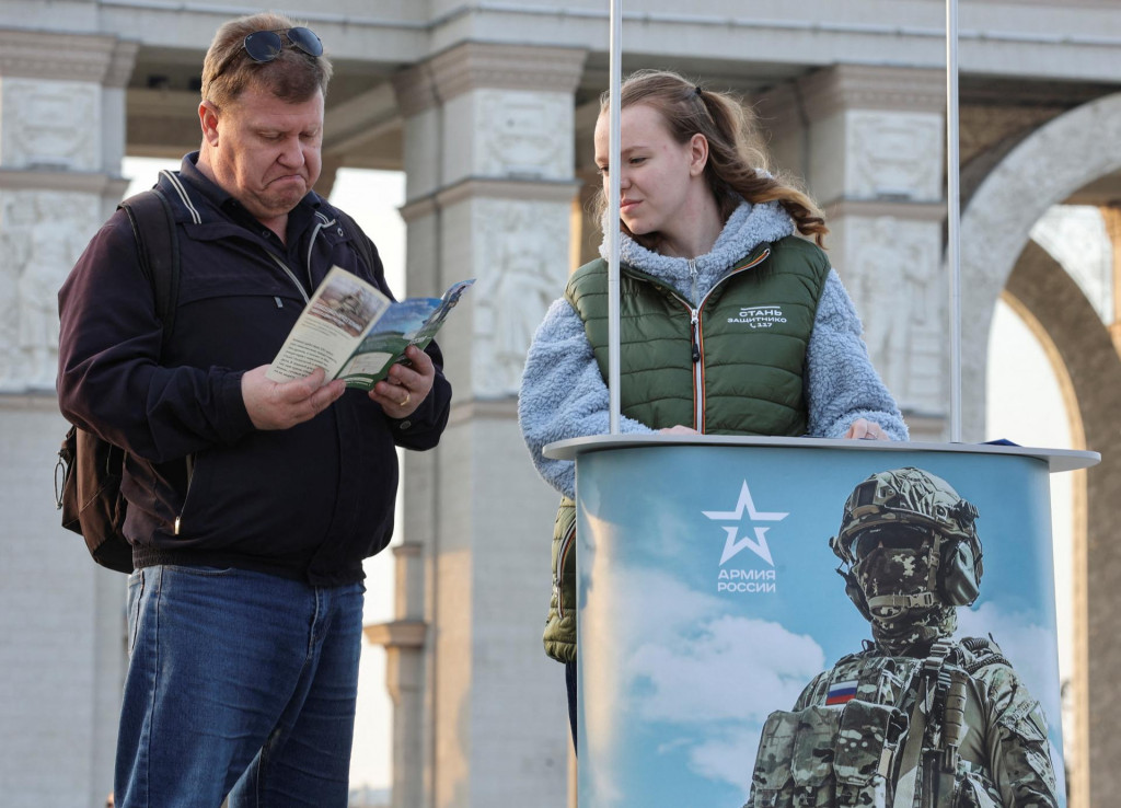 Muž číta leták od členky kampane propagujúcej službu v ruskej armáde v Moskve. FOTO: Reuters