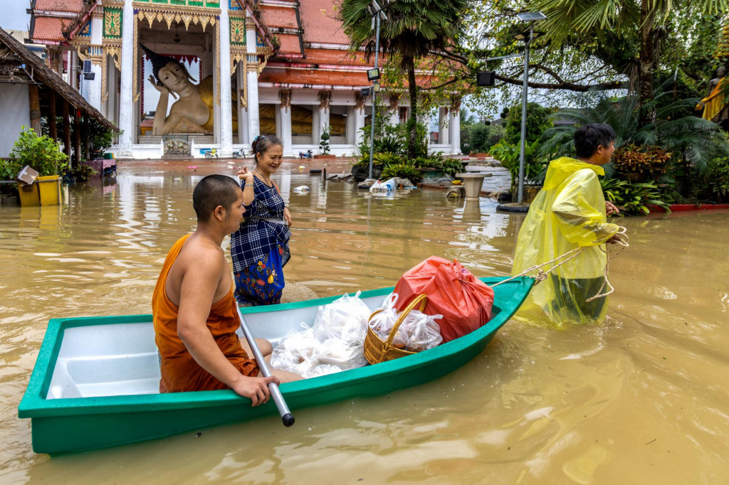 Budhistický mních a miestni obyvatelia sa brodia zaplavenou ulicou v thajskej provincii Songkhla. FOTO: Reuters