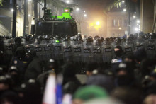 Policajti blokujú demonštratov, ktorí protestujú pred budovou parlamentu v gruzínskej metropole Tbilisi. FOTO: TASR/AP