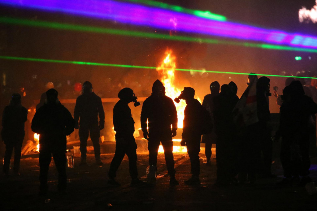 Ľudia s plynovými maskami sa zúčastňujú protestu proti rozhodnutiu gruzínskej vlády prerušiť rozhovory o vstupe do Európskej únie. FOTO Reuters