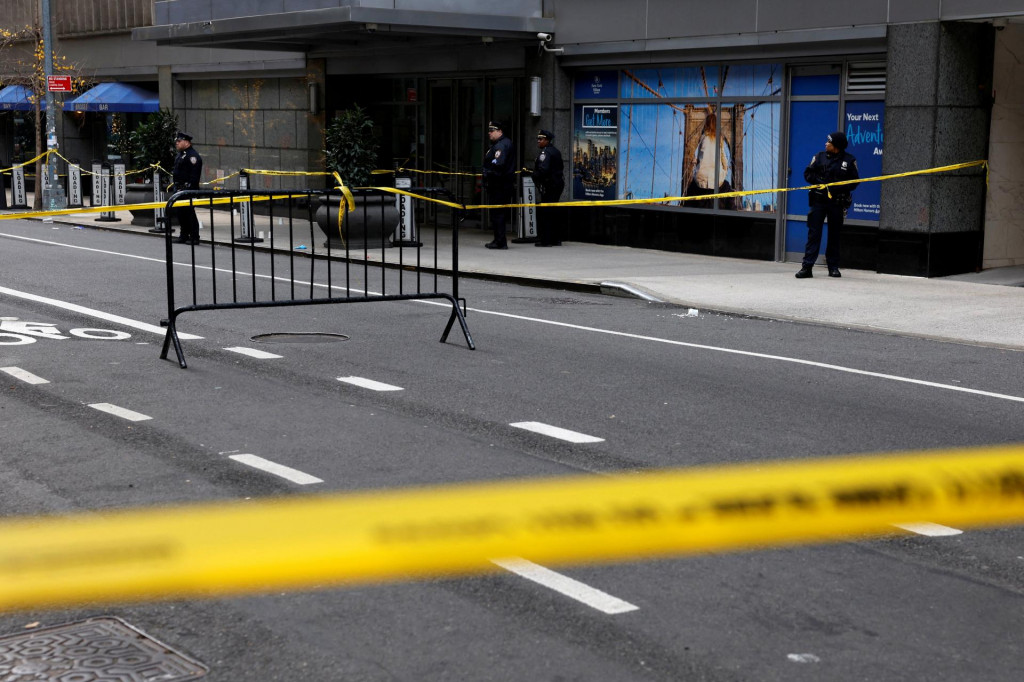 Policajti stoja blízko miesta, kde bol zastrelený generálny riaditeľ UnitedHealthcare Brian Thompson v Midtown Manhattan, v New York City, USA.