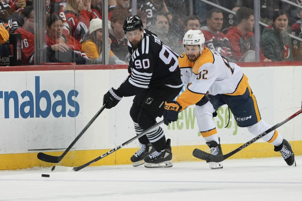 Slovenský hokejista v drese New Jersey Devils Tomáš Tatar (vľavo) a hráč Nashville Predators Tommy Novak bojujú o puk počas zápasu zámorskej NHL New Jersey Devils - Nashville Predators v Newarku. FOTO: TASR/AP