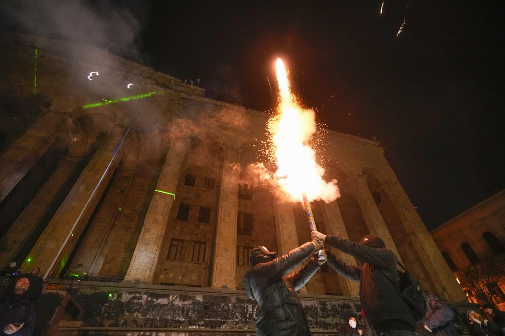 Demonštranti odpaľujú petardy počas protestu pred budovou parlamentu v gruzínskej metropole Tbilisi. FOTO: TASR/AP