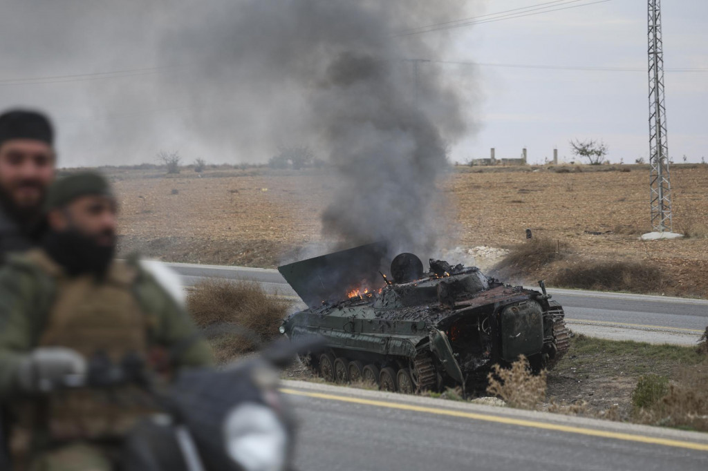 Sýrski opoziční bojovníci jazdia okolo horiaceho vládneho obrneného vozidla, južne od Hamá na severozápade Sýrie. FOTO: TASR/AP