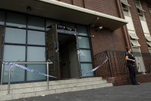 Policajtka stojí na stráži na mieste požiaru synagógy v austrálskom Melbourne. FOTO: Reuters/AAP