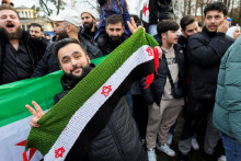 Muž drží reprezentáciu sýrskej opozičnej vlajky počas toho, ako oslavujú sýrski utečenci v Bonne v Nemecku. FOTO: REUTERS