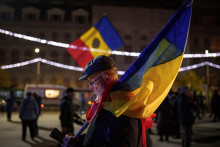 Muž, ktorý drží rumunskú vlajku, kontroluje svoj mobilný telefón na proeurópskom zhromaždení v Bukurešti. FOTO: TASR/AP