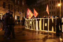 Zoradení policajti počas toho, ako krajne pravicoví demonštranti držia nápis a vlajky počas protestu v nemeckom Magdeburgu. FOTO: REUTERS