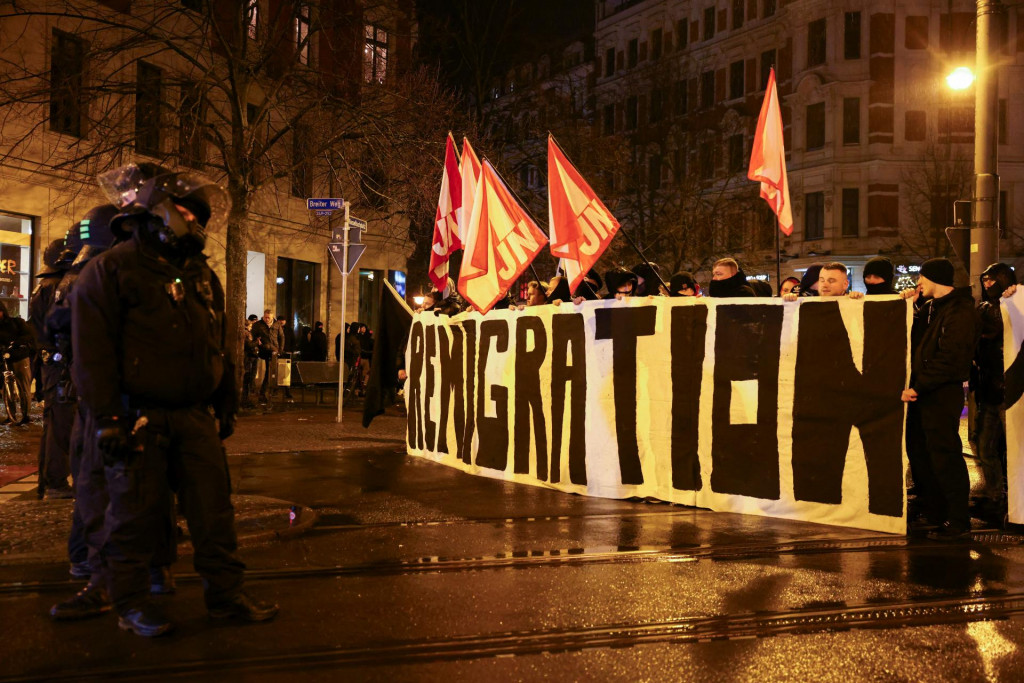 Zoradení policajti počas toho, ako krajne pravicoví demonštranti držia nápis a vlajky počas protestu v nemeckom Magdeburgu. FOTO: REUTERS