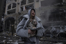 Ivanna zohrieva svojho psa pred horiacim vrakom osobného auta po útoku ruskej armády na ukrajinské hlavné mesto Kyjev. FOTO: TASR/AP