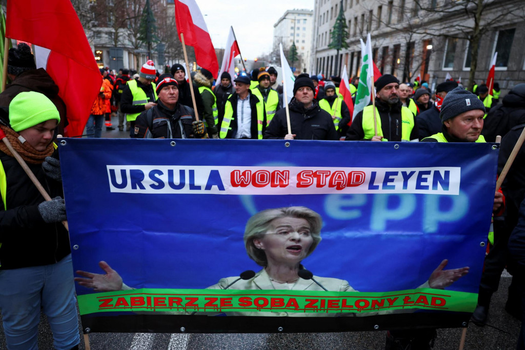 Ľudia držia transparent s nápisom: „Ursula-go-away-Leyen“, počas toho, čo farmári protestujú pred kanceláriou Komisie Európskej únie vo Varšave. FOTO: Reuters