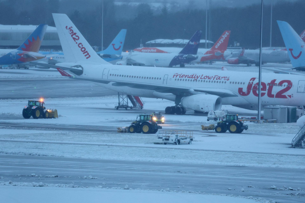 Zamestnanci používajú traktory na odpratávanie snehu na letisku v Manchestri. FOTO: Reuters