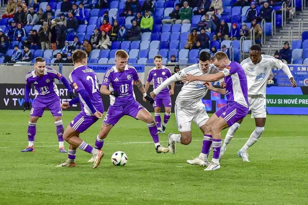 Hráči Komárna (vo fialovom) musia aktuálne riešiť aj nepríjemnosti nefutbalového charakteru. FOTO: skslovan.com