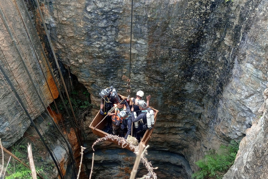 Potápači pomocou kladky vstupujú do uhoľnej bane, aby zachránili uväznených baníkov. FOTO: Reuters