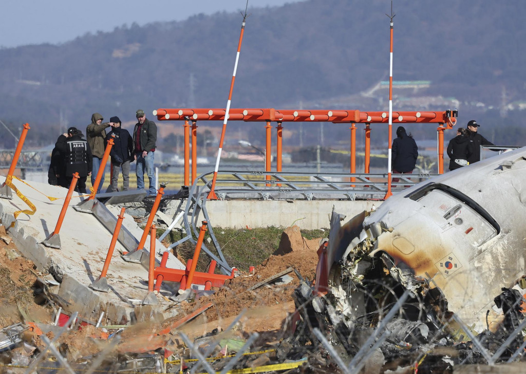 Americkí dopravní experti z NTSB a spoločný vyšetrovací tím USA a Južnej Kórey kontrolujú miesto nedeľňajšej leteckej nehody, ktorá si vyžiadala 179 obetí, na juhokórejskom medzinárodnom letisku Muan. FOTO: TASR/AP