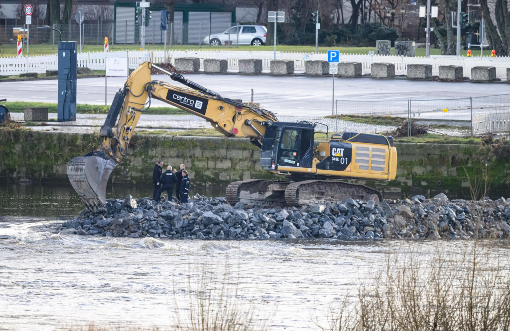 Policajti a zamestnanci úradu pre likvidáciu výbušnín stoja pred bagrom na stavenisku pri búraní časti zrúteného mosta Carolabrücke v Drážďanoch. FOTO: TASR/DPA